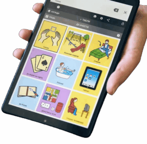a hand holding a phone or small tablet with nine colorful symbols and words used for communication