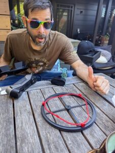 guy in rainbow sunglasses smiling and doing a big thumbs up at an outdoor picnic table