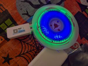 a gleaming wheel of blue and green lights with a  small battery pack attached