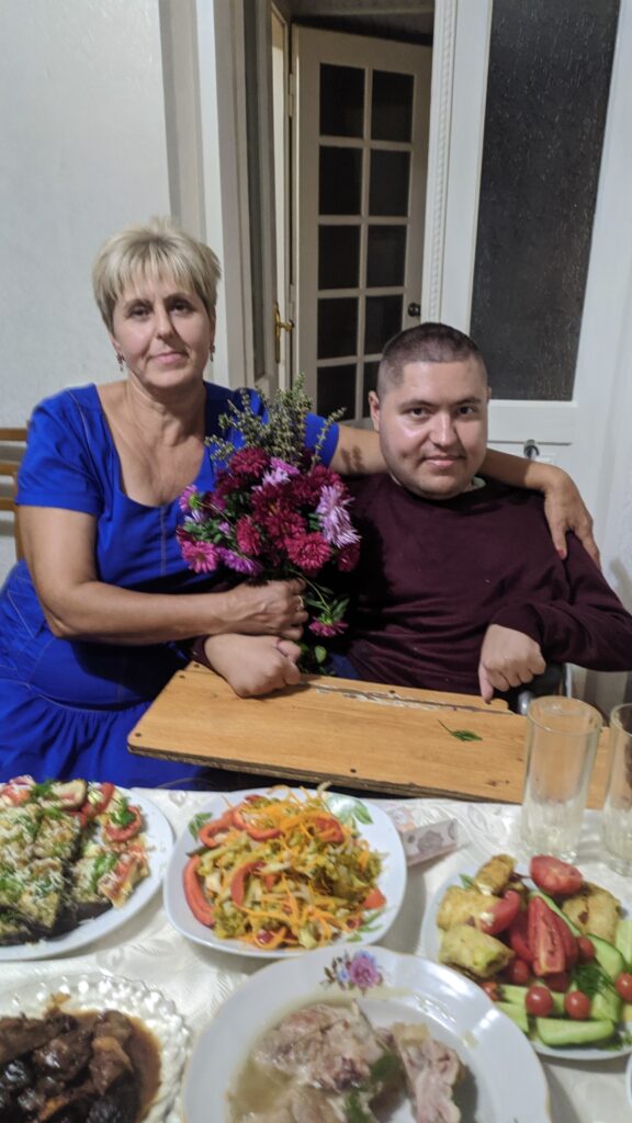 mother and son, dressed up for a party, with flowers and a beautiful home-made feast