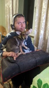 andrei, wheelchair user with dark hair, holding his dog Bobby