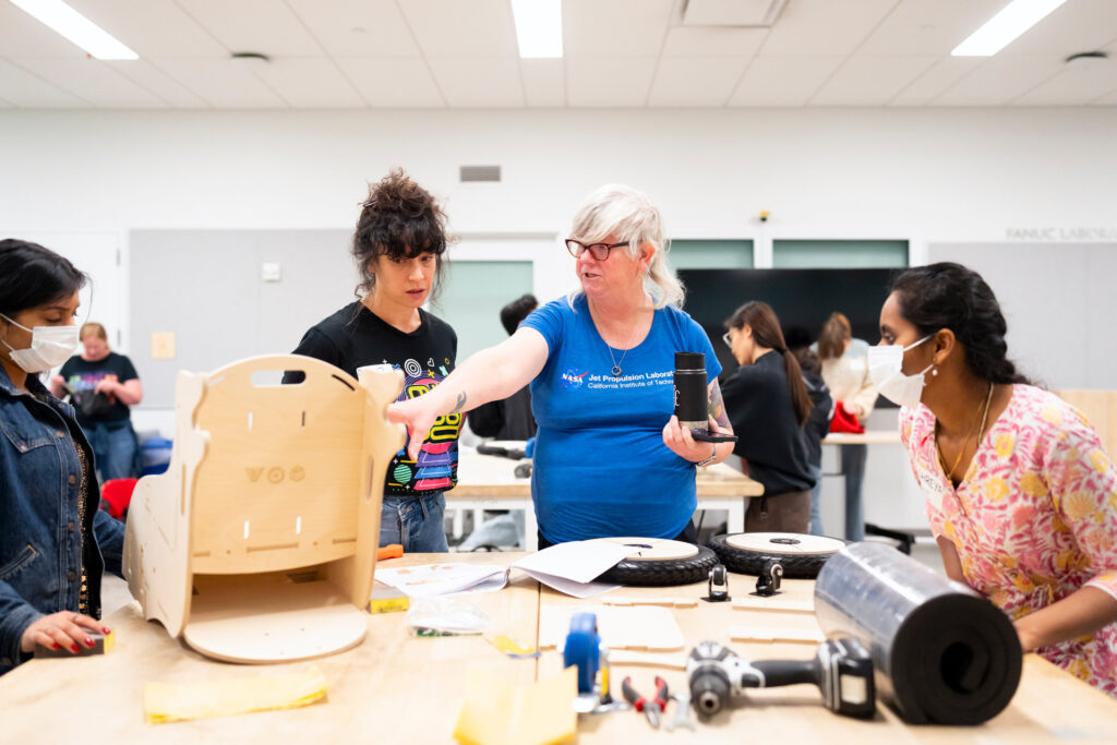 several people gathered around a wheelchair being built on a large workbench