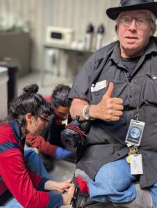 Dana and Angello crouching to fix a powerchair users's hand brakes