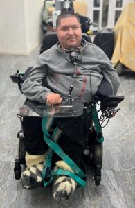 man with powerchair smiling slightly