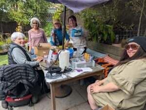 a group of people gathered around a patio table laden with tools