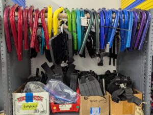 colorful wheelchair footrests arranged in a rainbow, hanging on a wooden dowel 