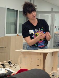 a women with tools standing over a half built plywood wheelchair