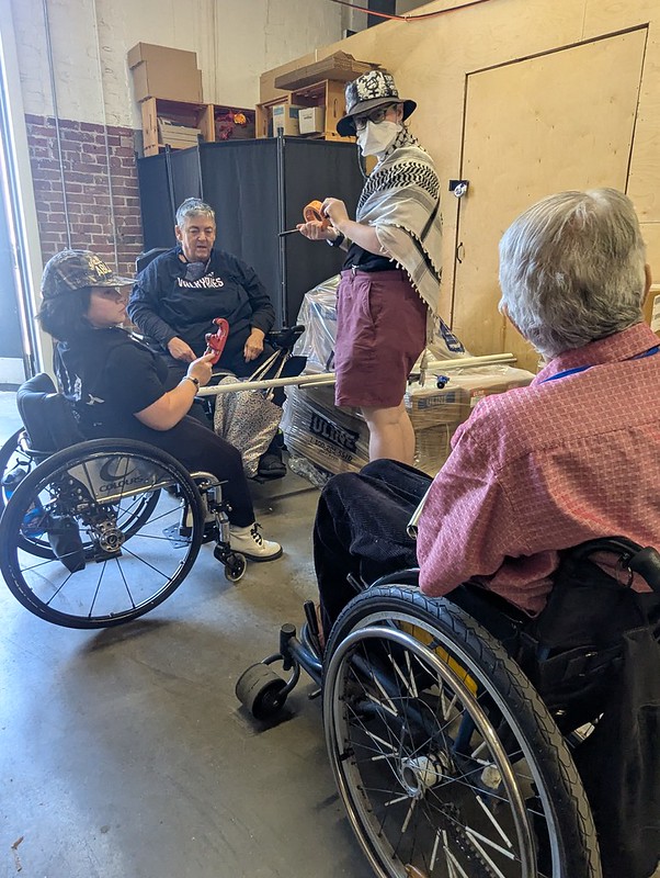 several wheelchair users and one standing person with pipe cutters