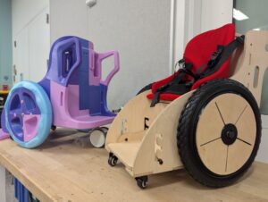a 3d printed toddler wheelchair next to a plywood one