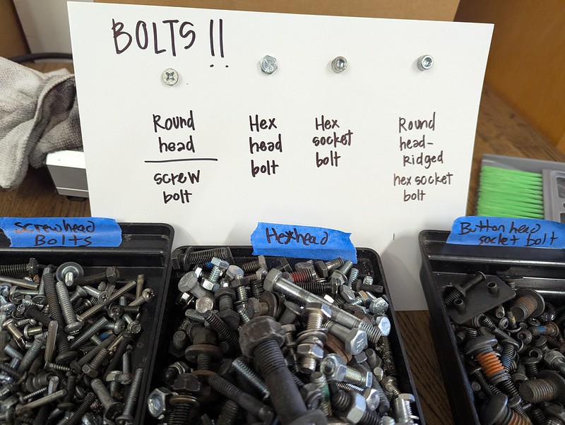Cardboard sign with bolts attached, explaining the differences in how to manipulate the different shapes